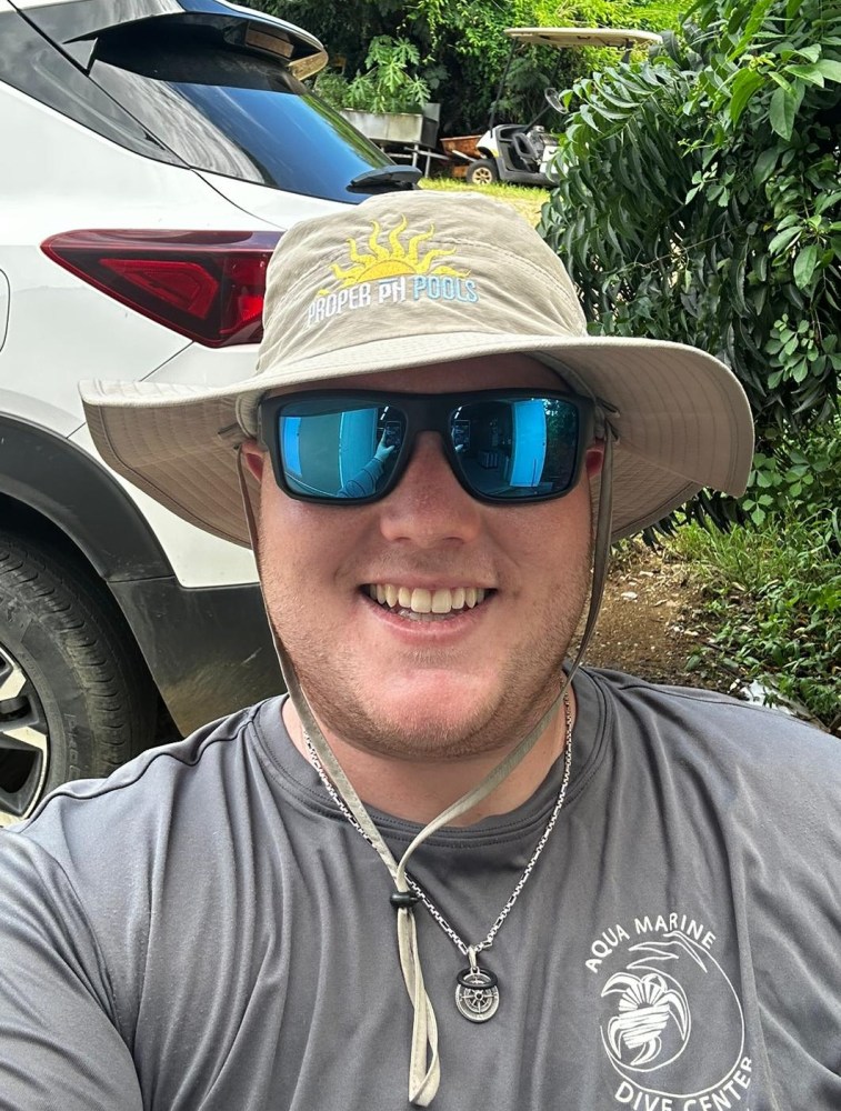 a man wearing a hat and sunglasses posing for the camera