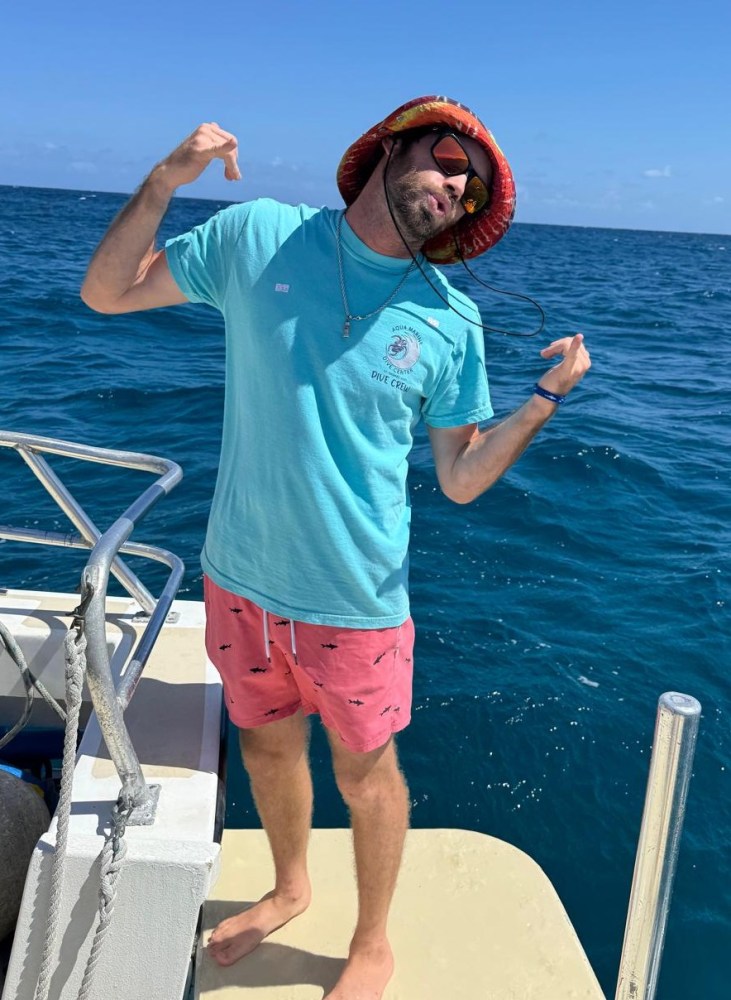 Person in casual attire posing on a boat with ocean in the background.